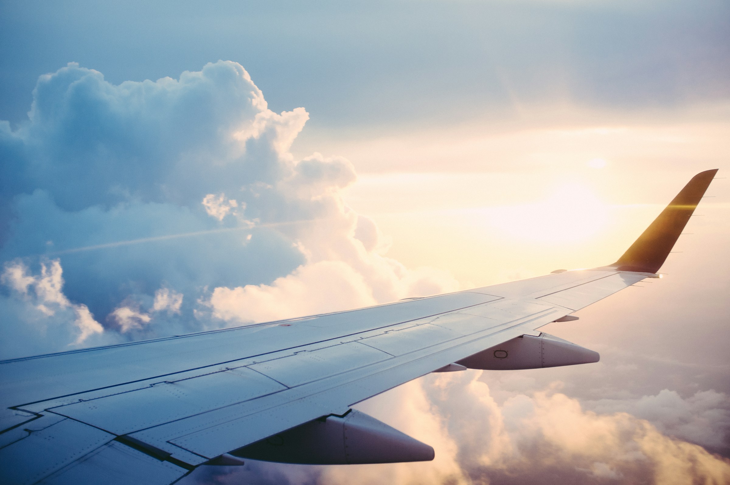 Aircraft wing above a cloud-covered landscape in warm evening light